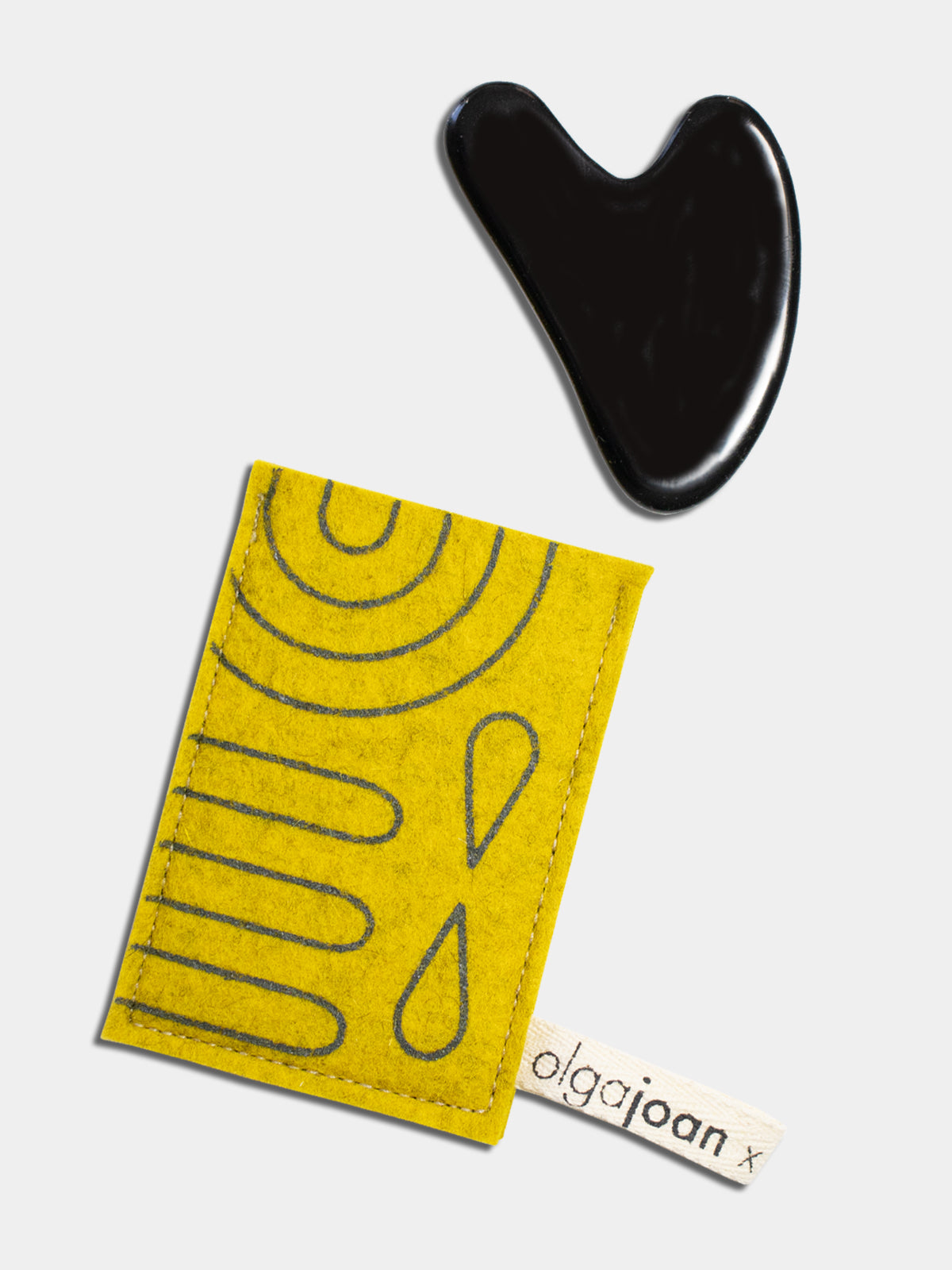 Black heart-shaped obsidian gua sha tool with yellow felted wool protector featuring dark gray-green graphic pattern.